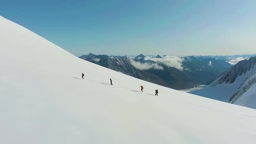 Eine Gruppe von Alpinisten rückt als Seilteam in den verschneiten Bergen vor. Luftbild