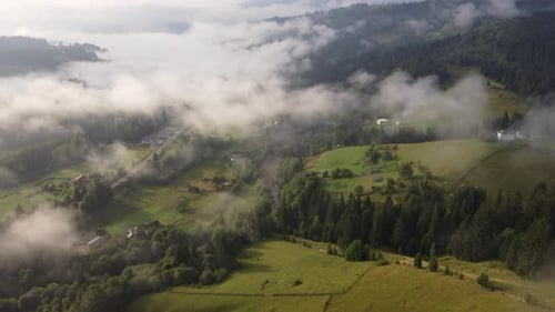 Flight Over a Small Village in the Mountains in the Summer Morning in the Fog