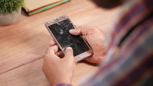 человек держит в руках сломанный смартфон