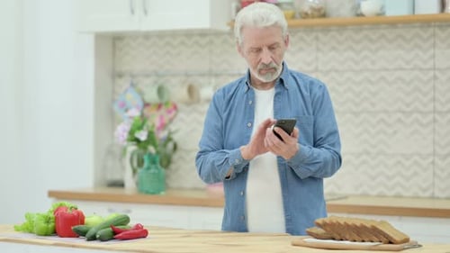 Silver Haired Man Using Mobile Phone in Kitchen