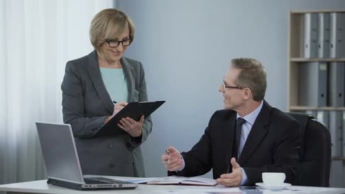 Woman Reviews Documents with Man in Office Setting