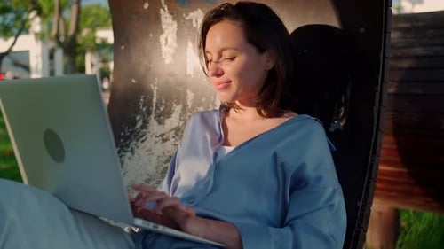 Happy Brunette Woman Using Laptop Computer While Sitting in Park
