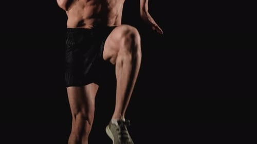 Shirtless Man Running in Place Against Black Background