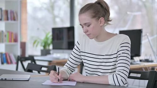 Thoughtful Young Woman Doing Paperwork in Library