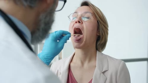 Woman Receives Throat Exam by Doctor in Clinic