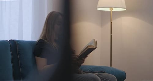 Junge hübsche Frau liest am Sonntagabend ein Buch und ruht sich zu Hause aus. Intelligente Dame entspannt sich