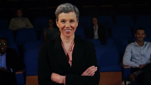Confident businesswoman standing with arms crossed in auditorium