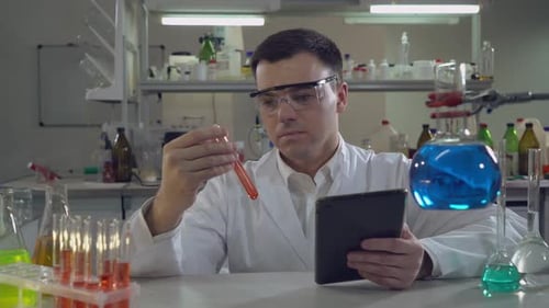 Scientist Holding Test Tube and Tablet in Lab