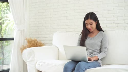 Woman Works on Laptop at Home on Couch