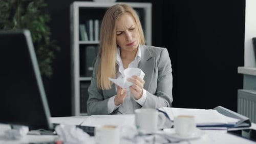 Frustrated Woman Crumples Paper at Office Desk