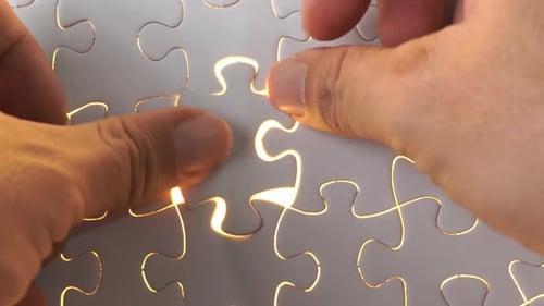 A man's hand solve the last piece of puzzle.