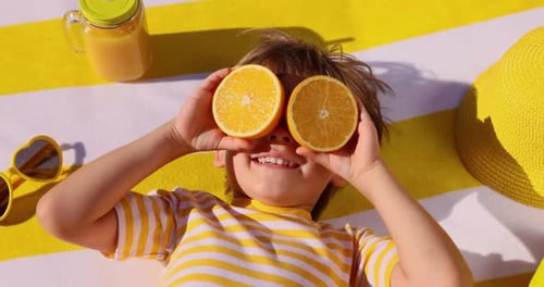 Happy Boy with Oranges at the Beach