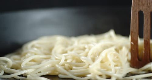Boiled Pasta Spaghetti Stirred with Wooden Spatula on the Pan