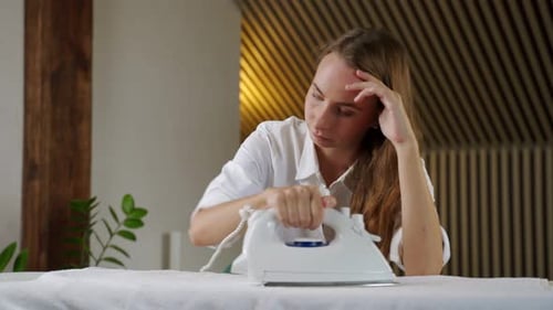 Tired Woman Ironing Clothes at Home