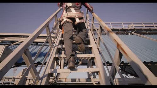 Worker Climbing Metal Stairs at Industrial Site