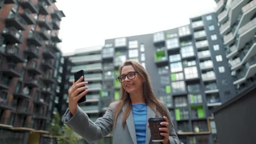 Formally Dressed Woman Walking Down the Street in a Business District with Coffee in Hand and