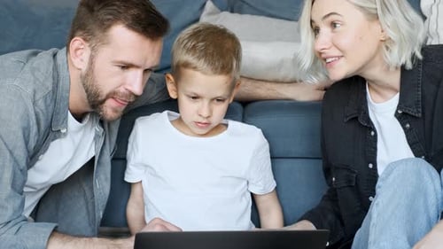 Happy family looking at videos on laptop while kid point at screen and talk smiling