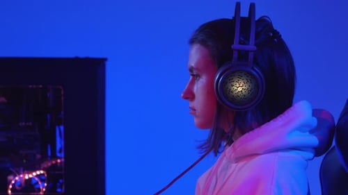 Woman Gaming with Headphones in Blue Lit Room