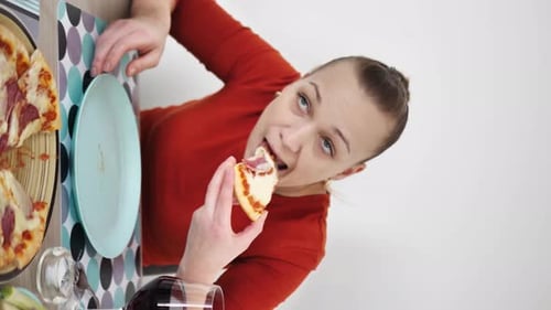 Woman Eats Pizza at Table Indoors