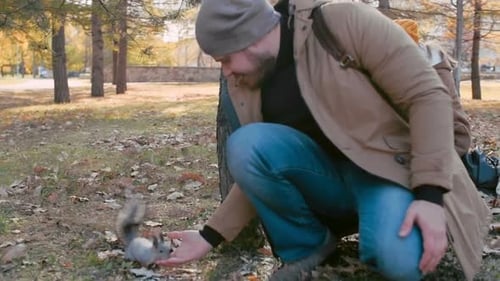 Man Feeding Squirrel in Autumn Park with Family