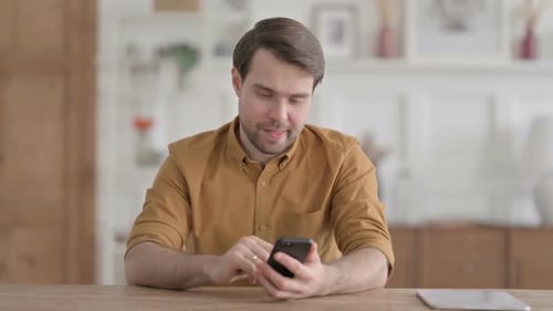 Man Uses Smartphone, Reacts to Bad News