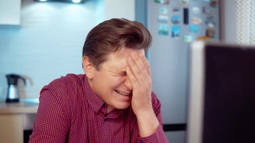 Mann weint bei der Arbeit am Computer