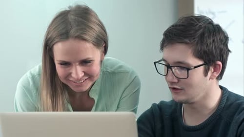 Woman and Man Collaborating at Laptop in Office