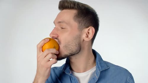 Young Adult Bites Into a Juicy Orange