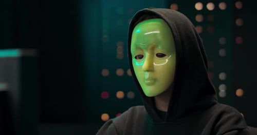 Masked Hacker Working on Computer in Dark Room