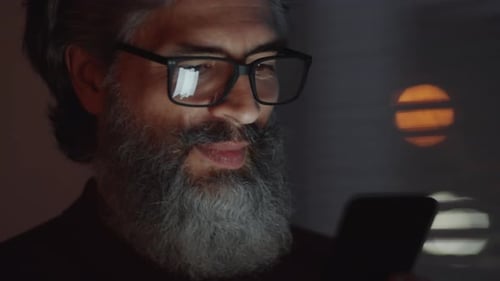 Bearded Businessman Using Smartphone in Darkness