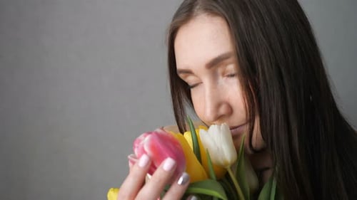Happy Young Woman Smelling a Bouquet of Tulips