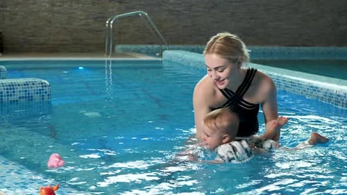 Junge Mutter Schwimmlehrerin und glückliches kleines Mädchen im Pool