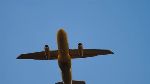 Yellow Aircraft Flying Overhead in Clear Blue Sky