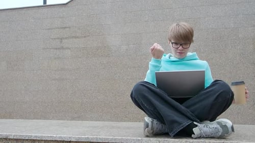 Young Woman Blogger Sits in Front of a Laptop Monitor Outdoors in the City