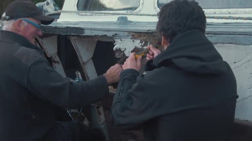 Men Repairing a Boat Together Outdoors