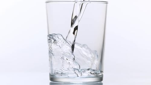 980025 Se vierte agua en un vaso sobre un fondo blanco, Cámara lenta