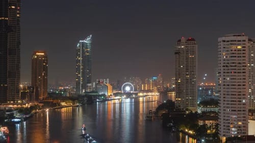 Time lapse of ferris wheel by Chao Phraya River in financial district and skyscraper buildings