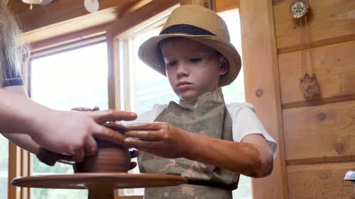 Boy Learning Pottery on Wheel with Instructor
