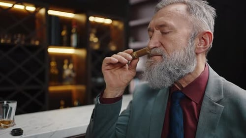 Wealthy Senior Gentleman Smelling Cigar Enjoying Aroma of Expensive Tobacco Sitting at Bar Counter