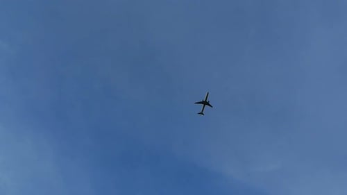 Airplane Flies Across Bright Blue Sky Overhead
