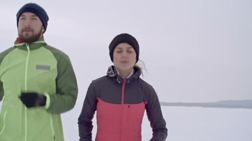 Athletic Couple Jogging on a Snow-Covered Field