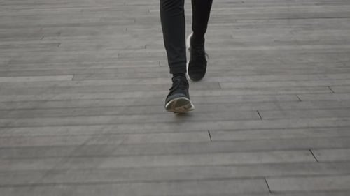 Legs Walking in Black Shoes on a Wooden Path