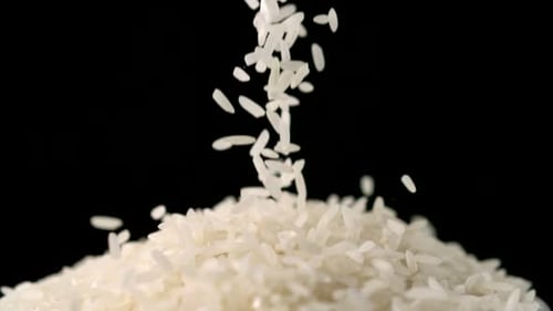 Rice Grains Falling Against Black Background