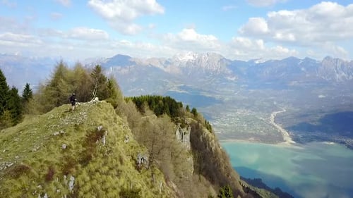 Aerial drone view of a hiker and his dog on a dirt road with green hills.