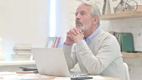 Senior Man Contemplating at Desk with Laptop