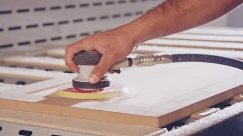 Slow motion of a worker polishing a cabinet door in a furniture factory