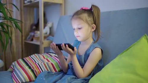 Little Girl Using a Smartphone on the Couch