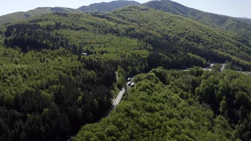 Aerial View Of Vehicles Driving On Winding Mountain Road With Dense Forest In Romania