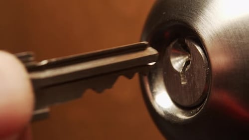 Macro shot of a silver key inserted into lock of an internal doorknob lock