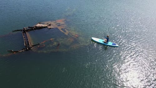Woman Paddleboarding Near Sunken Ship, Aerial View